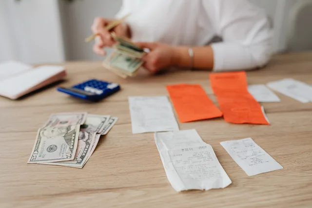 A person using a calculator and cash to plan a household budget. Forbrugsmønstre i Danmark: Hvilke offentlige statistikker findes?